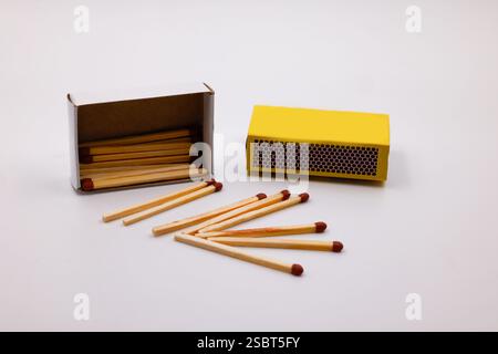 Boîte d'allumettes ou de baguettes en bois isolées sur fond blanc. Carton jaune assorti d'un contenant d'allumettes à bout brun et d'une bande de grève Banque D'Images