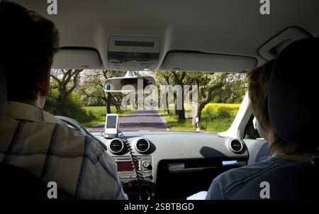 Couple conduisent le long de la route avec le pommier en fleur Banque D'Images