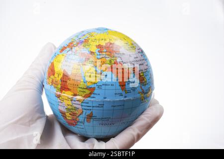 Le concept de pandémie. Mains en gants blancs tenant un globe Banque D'Images