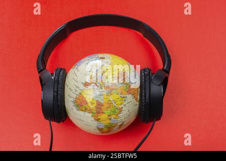 Micro-casque sur globe isolé sur le rouge Banque D'Images