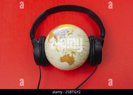 Micro-casque sur globe isolé sur le rouge Banque D'Images
