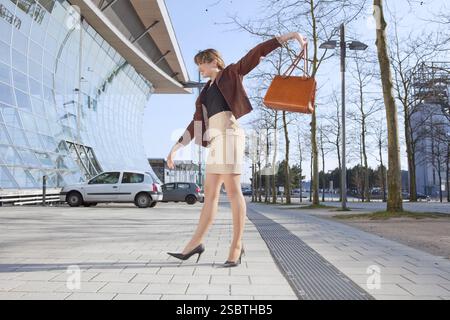 Jeune femme gaie se dresse sur rue en ville Banque D'Images