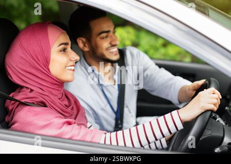 Mari arabe attentionné enseignant à sa femme musulmane au Hijab à conduire une voiture Banque D'Images