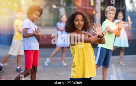 Joyeuse fille Tween noire dansant avec des amis dans la rue de la ville Banque D'Images