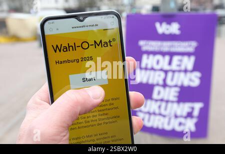 Ein Mann hält vor einem Wahlplakat der Partei Volt ein smartphone in der hand, auf dem der Wahl-O-Mat zur Bürgerschaftswahl in Hamburg geöffnet ist. Eppendorf Hambourg *** Un homme tient un smartphone devant une affiche électorale du parti Volt, sur laquelle le Wahl O Mat pour les élections législatives de Hambourg est ouvert Eppendorf Hambourg Banque D'Images