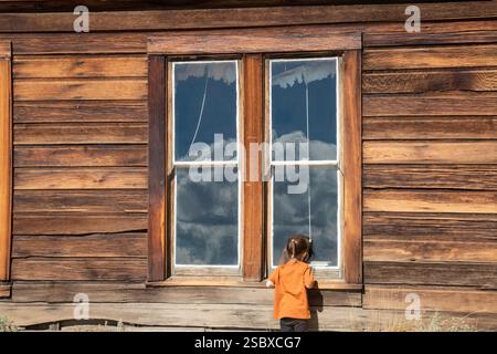 Bodie, Californie - Un enfant regarde par la fenêtre de l'ancienne école du parc historique de Bodie State. Le parc conserve les restes d'une mine d'or t Banque D'Images