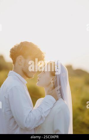 Couple partageant un moment chaleureux et romantique au soleil avec un ensemble doux et des expressions tendres Banque D'Images