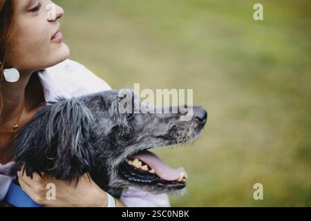Gros plan d'une femme heureuse avec un chien, dans un cadre naturel lumineux Banque D'Images