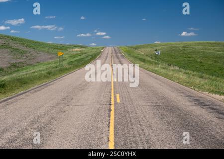 Tronçon solitaire d'autoroute approchant une colline zone interdite de passage sur les hautes plaines du comté de Day, Dakota du Sud Banque D'Images