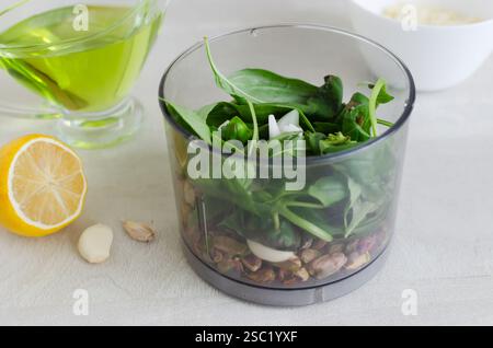 Pistaches rôties au basilic et à l'ail dans un bol de mixeur. Le processus de fabrication du pesto de pistache. Orientation horizontale. Mise au point sélective. Banque D'Images