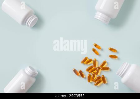 Complément alimentaire Oméga 3. Pilules de santé versées à partir de bouteilles blanches médicales sur fond bleu. Vue de dessus. Concept de santé. Banque D'Images