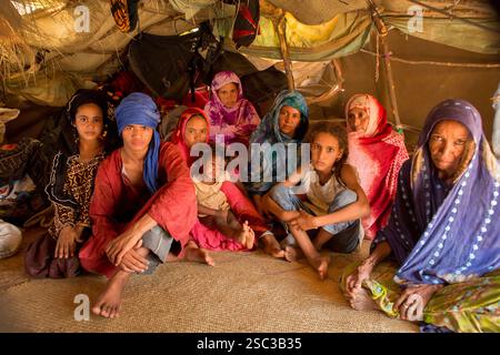 Camp de Mentao pour réfugiés maliens, près de Gibo, nord du Burkina Faso mai 2012 : Fatma Mohamed, au centre, avec deux sœurs. Elle et sa sœur Aissa, qui est partie, ont toutes deux perdu les maris qui étaient dans l'armée malienne pendant le conflit en février 2012. Les Arabes vivent dans une section séparée du camp. Les réfugiés, pour la plupart Touaregs, sont aujourd’hui plus de 60 000 au Burkina Faso seulement, et continuent d’arriver quotidiennement dans les camps, suite au chaos politique créé par le coup d’État du 22 mars 2012 par des officiers maliens subalternes. Photographie de Mike Goldwater Banque D'Images