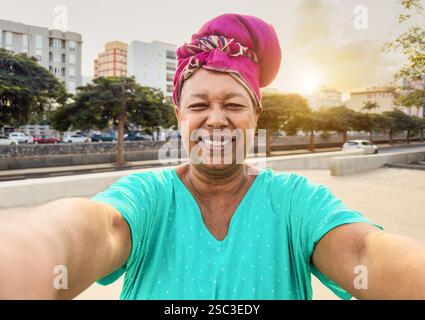 Femme âgée africaine heureuse prenant selfie tout en portant des vêtements traditionnels - Joyful vieillesse style de vie et concept de vacances de voyage - Focus sur le visage Banque D'Images