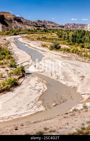 Une rivière coule à travers un désert. L'eau est boueuse et le sol est sec. Des arbres poussent le long de la rivière Banque D'Images