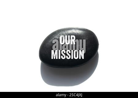 Notre message de mission écrit sur pierre noire sur fond blanc. Conceptuel notre symbole de mission. Copier l'espace. Banque D'Images