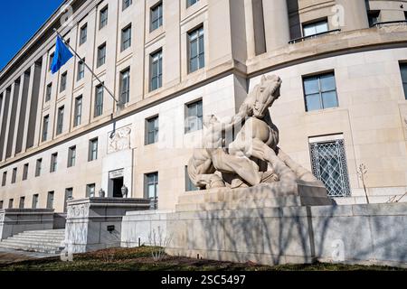 Sculpture Man Controlling Trade au Federal Trade Commission Building à Washington DC | WASHINGTON DC, États-Unis — L'un des deux groupes de sculptures en calcaire « Man Controlling Trade » de Michael Lantz garde l'entrée du Federal Trade Commission Building au sommet du Triangle fédéral. Sculpté sur le site et dévoilé en 1942, le groupe représente un homme tendu retenant un cheval d'élevage, une allégorie pour la réglementation gouvernementale du commerce. Le bâtiment lui-même, conçu par Edward H. Bennett et achevé en 1938, était le dernier des structures originales du Triangle fédéral construites. Banque D'Images