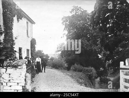 Un groupe de personnes sur une route étroite, à côté d'une maison blanche, Aberystwyth, Ceredigion, pays de Galles. C1900s, monochrome : d'une importante collection historique de photographies originales et inattribuées de l'albumen de la fin de l'époque victorienne au début de l'époque édouardienne : une tournée britannique comprenant le Staffordshire, le Warwickshire et le nord du pays de Galles. La qualité des originaux était variable et la plupart étaient autour de 108x165mm. Banque D'Images
