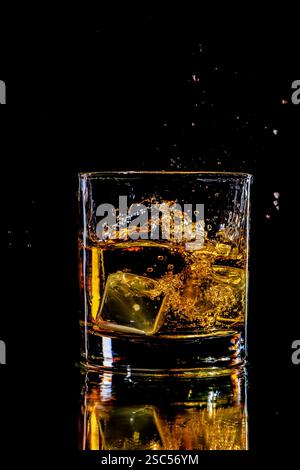 whisky éclabousser dans un verre avec deux glaçons Banque D'Images