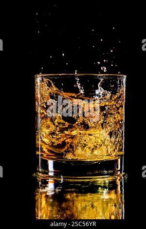 whisky éclabousser dans un verre avec deux glaçons Banque D'Images