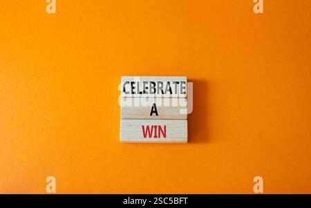 Célébrez un symbole gagnant. Les mots conceptuels célèbrent une victoire sur des blocs de bois. Beau fond orange. Et célébrez un concept gagnant. Copier l'espace. Banque D'Images
