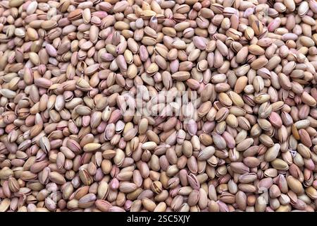 Pistaches grillées en coquille. Fond empilé d'arachides alimentaires naturelles. Banque D'Images