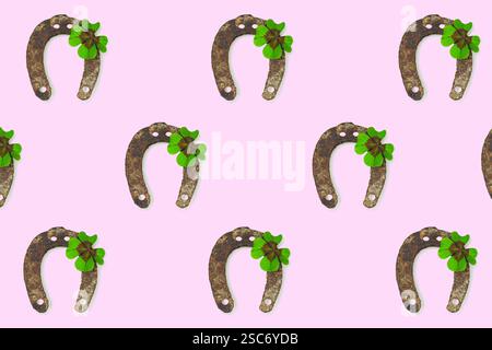 Motif répété en fer à cheval et en trèfle. Fer à cheval et trèfle à quatre feuilles isolés sur fond rose. Prog Patrick's Day Banque D'Images