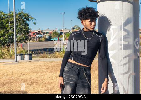 Un jeune Africain hispanique appuyé contre une colonne de ventilation reposant dehors. Banque D'Images