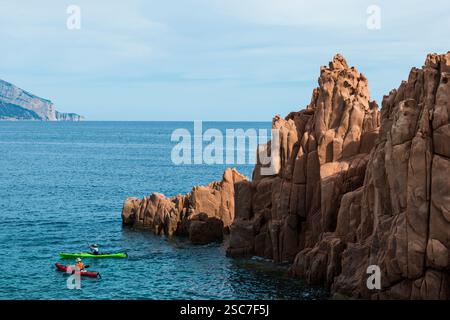 Roches rouges au bord de la mer et kayaks, roches porphyriques, Arbatax, Tortolì, province d'Ogliastra, Sardaigne, Italie Banque D'Images