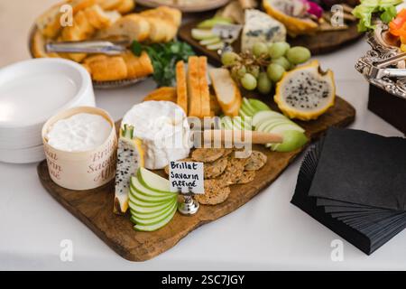 Un plat magnifiquement arrangé avec des fromages assortis, des fruits frais et des collations est présenté lors d'un événement joyeux. La présentation met en évidence la couleur Banque D'Images