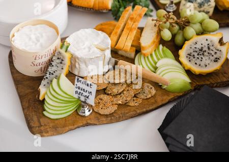 Un plateau de fromages magnifiquement arrangé comprend un assortiment de fromages, raisins frais, tranches de fruits de dragon, craquelins croustillants et tranches de pommes vertes, p Banque D'Images