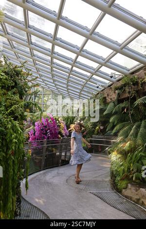 Fille filant dans le jardin intérieur d'orchidées de serre Banque D'Images