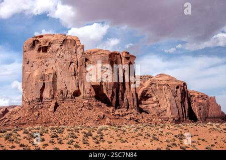 Une grande formation rocheuse avec un ciel nuageux en arrière-plan. Le ciel est principalement bleu avec quelques nuages Banque D'Images