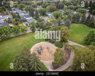 Parc avec aire de jeux et chemin. Le parc est entouré de maisons. Le ciel est nuageux Banque D'Images