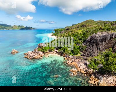 Vue aérienne sur la plage tropicale, les formations rocheuses et la forêt verdoyante le long de la côte. Curieuse, Seychelles. Banque D'Images