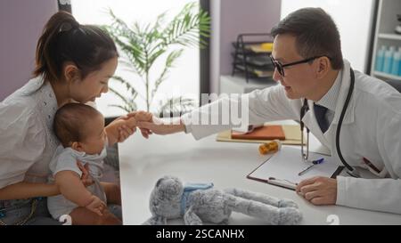 Femme tenant le bébé garçon visite un pédiatre masculin amical dans la clinique de l'hôpital, avec un accent sur les soins familiaux et les liens dans un cadre intérieur professionnel. Banque D'Images
