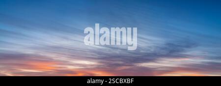 Un grand panorama du ciel avant le coucher du soleil, bas nuages rayés de couleur rouge vif. Banque D'Images
