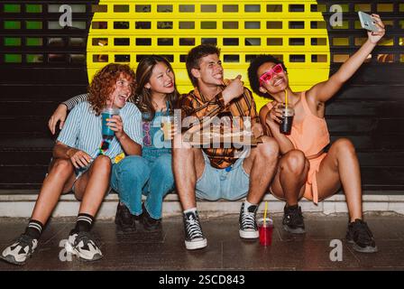 Amis sortant le soir et faisant la fête. Les jeunes se réunissent en plein air le week-end et célèbrent ensemble avec des cocktails colorés et piz Banque D'Images