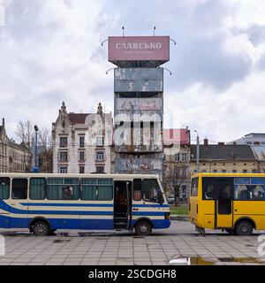 Lviv, Ukraine – 24.03.2024 : petits bus régionaux devant une tour de panneaux d’affichage usagée et inutilisée à l’arrêt de bus Prymiskyi Vokzal sur la rue Horodotska Banque D'Images