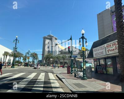 Une vue sur la rue animée dans le centre-ville de la Nouvelle-Orléans avec des rues bordées de palmiers, une architecture historique, des lampadaires et des piétons profitant d'une journée ensoleillée Banque D'Images