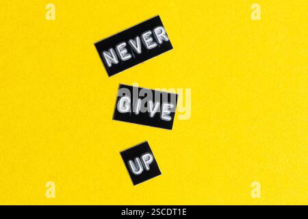 N'abandonnez jamais le texte sur fond jaune. Concept de motivation Banque D'Images