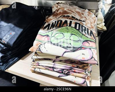 Kiev, Ukraine - 05 février 2025 : pile de t-shirts mandaloriens imprimés avec le design Baby Yoda soigneusement exposés en magasin. Banque D'Images