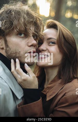 Gros plan d'un couple souriant dans la forêt partageant un moment affectueux Banque D'Images