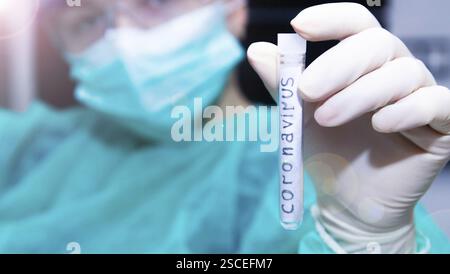 Main gantée tenant un tube à essai marqué au coronavirus Banque D'Images