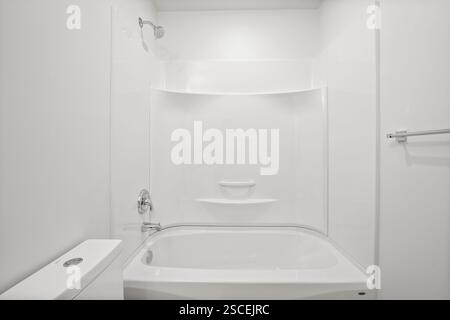 Une salle de bains blanche avec toilettes blanches et baignoire blanche. La salle de bain est vide et propre Banque D'Images