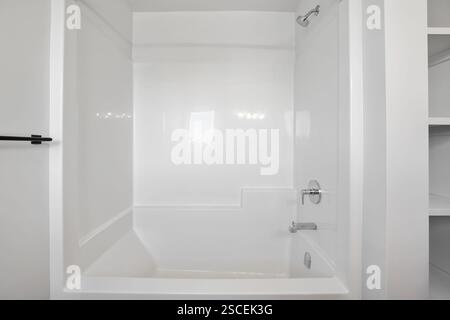 Une salle de bains blanche avec une baignoire blanche et une douche blanche. La douche est vide et la baignoire est également vide Banque D'Images
