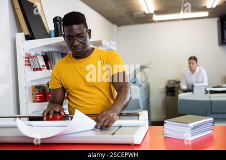 Portrait d'un employé positif de la maison d'impression avec des projets entre les mains Banque D'Images