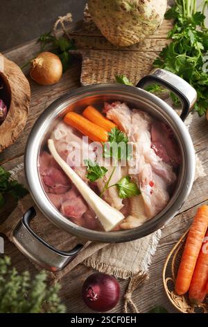 Dos de poulet crus, foie et légumes frais dans une casserole d'eau - ingrédients pour bouillon d'os ou soupe Banque D'Images