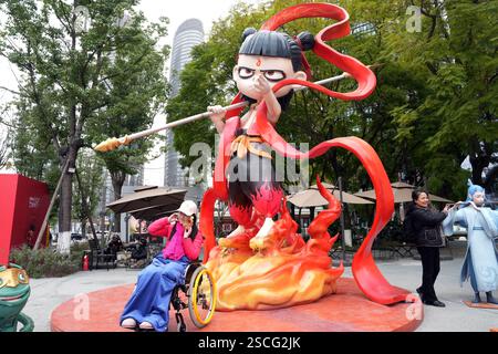 Chengdu, China.6th février 2025. Un visiteur pose pour une photo avec une sculpture de ne Zha, une figure mythologique chinoise, sur l'avenue Jiaozi le 6 février 2025 à Chengdu, province chinoise du Sichuan. Le film d'animation ne Zha 2 a surpassé l'épopée de guerre de 2021 « la bataille au lac Changjin » pour devenir le film le plus rentable de tous les temps en Chine. Crédit : an Yuan/China News Service/Alamy Live News Banque D'Images