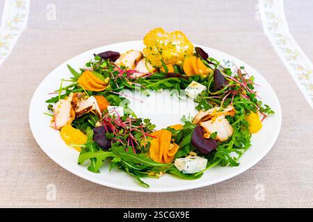 Une salade magnifiquement agencée présente des légumes vibrants, y compris des betteraves, de la courge et du fromage sur un lit de roquette. La présentation colorée améliore Banque D'Images
