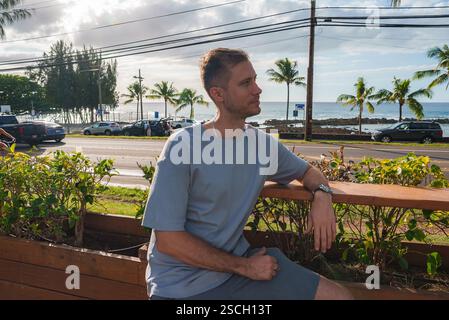Homme assis sur le banc avec l'océan et les palmiers à Hawaï Banque D'Images